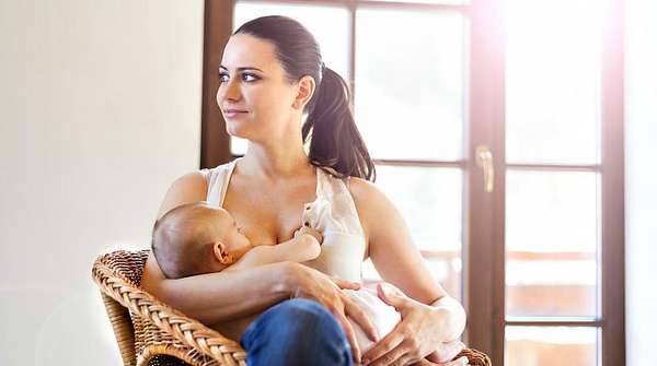 Девушка кормит малыша грудью